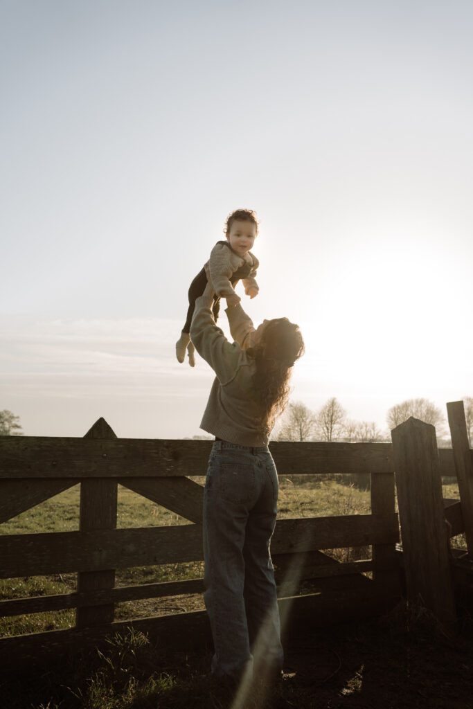 motherhood shoot - mama tilt baby op bij een hout hek